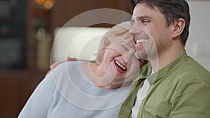 Rack focus from cheerful laughing senior mother to smiling adult son hugging parent talking. Happy Caucasian man and