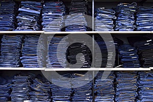 Rack with folded jeans, a lot of jeans, lying on a shelf in the store, textural background