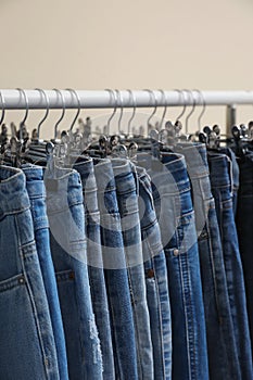 Rack with jeans on color background, closeup