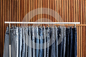 Rack with jeans on wooden background