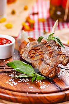 Rack of lamb fried with aromatic olive oil, herbs and spices on wooden board.