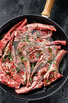 Rack of lamb marinated with thyme and mint , raw meat with bone. Organic lamb meat. Black background. Top view