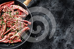 Rack of lamb marinated with thyme and mint , raw meat with bone. Organic lamb meat. Black background. Top view. Copy space