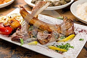 Rack of lamb on white plate with vegetalbes close up photo