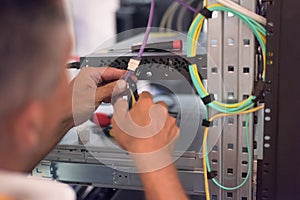 Rack Mounted Servers In A Server Room, man work with lan or network cables