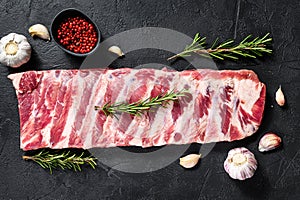 Rack of raw pork spare ribs seasoned with  spices. Black background. Top view