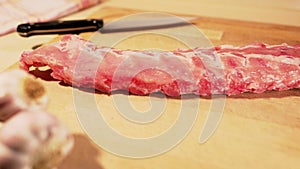 Rack of spareribs being placed on a wooden board
