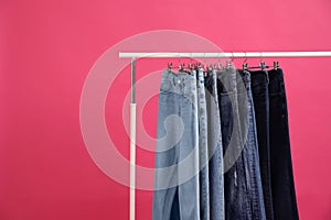 Rack with stylish jeans on background