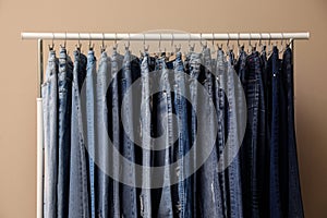 Rack with stylish jeans on background
