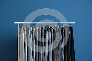 Rack with stylish jeans on blue background