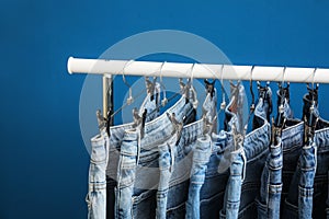 Rack with stylish jeans on blue background