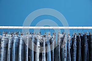 Rack with stylish jeans on blue background