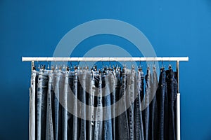 Rack with stylish jeans on blue background