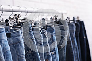 Rack with stylish jeans on light background