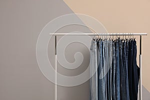 Rack with stylish jeans near color wall