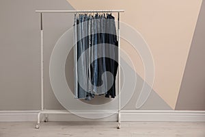 Rack with stylish jeans near color wall