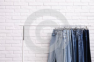 Rack with stylish jeans near wall