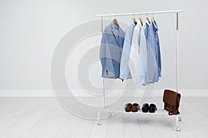 Rack with stylish men`s clothes in room