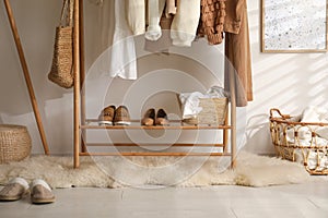 Rack with stylish shoes and women`s clothes in dressing room. Modern interior design
