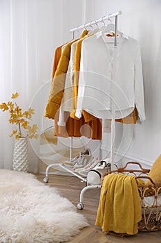 Rack with stylish warm clothes, shoes and accessories in modern dressing room