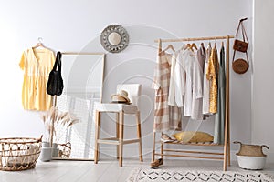 Rack with stylish women`s clothes and mirror. Interior design