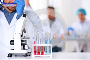 Rack with test tubes and microscope on table in laboratory, space for text.