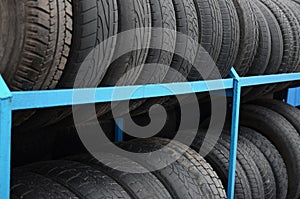 Rack with variety of car tires in automobile store. Many black tires. Tire stack background