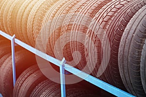 Rack with variety of car tires in automobile store. Many black tires. Tire stack background