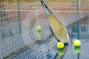 Racket leaning on net and wet tennis balls