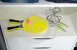 Rackets with a ball for beach tennis in the closet, a sports jump rope.