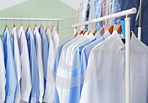 Racks with clean clothes on hangers after dry-cleaning