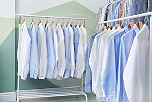 Racks with clean clothes on hangers after dry-cleaning