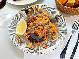 Racy seafood paella with mussels, squid rings and lemon