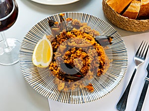 Racy seafood paella with mussels, squid rings and lemon photo