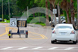 Radar speed limit indicator sign showing 30 proving a passing car is speeding as it drives down the road in a school zone