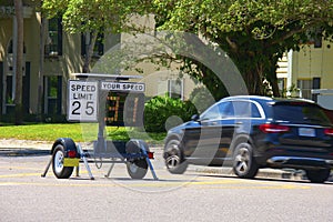 Radar speed limit indicator sign showing a passing car is speeding as it drives down the road
