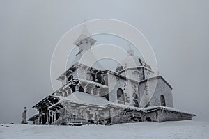 Radhost mountain with Chapel of St. Cyril and Methodius,Beskids,Czech republic.Winter landscape,foggy snowy day.Frozen wooden