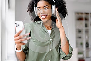 A radiant African-American lady with a joyful expression listens to music on her headphones