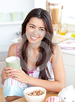Radiant asian woman holding a cup sitting at home