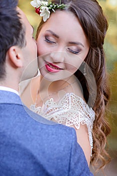 Radiant bride closes her eyes while groom kisses her cheek