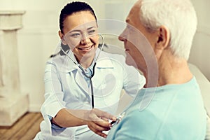 Radiant female nurse using stethoscope while checking lungs