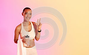 Radiant fitness enthusiast showing a peace sign while holding a water bottle