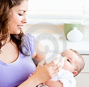 Radiant mother feeding her adorable son at home