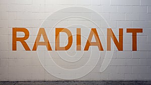 RADIANT is painted in bold orange letters on a white brick wall in the parking garage on Victory Park Lane, Dallas, Texas