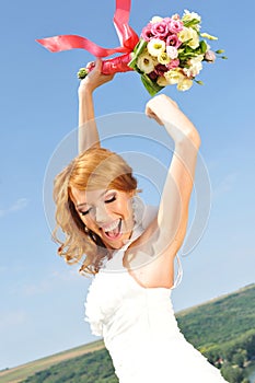 Radiant red haired bride raises bouquet in the air