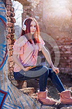 Radiant Redhead Woman Enjoying Music on Digital Tablet Against Sunset Ruins