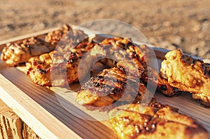 Radiant Sunlight Highlights Char-Grilled Chicken Slices on Wooden Tray, Ready to Tempt the Palate