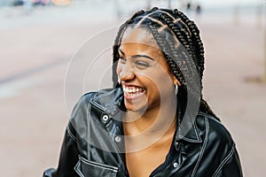 Radiant woman with braided hair laughing in a casual outdoor setting.