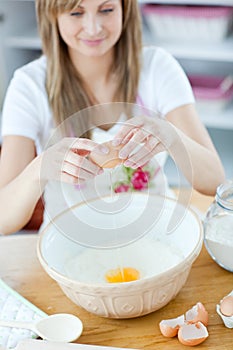 Radiant woman breaking eggs in a bowl