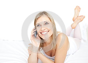 Radiant woman talking on phone lying on her bed